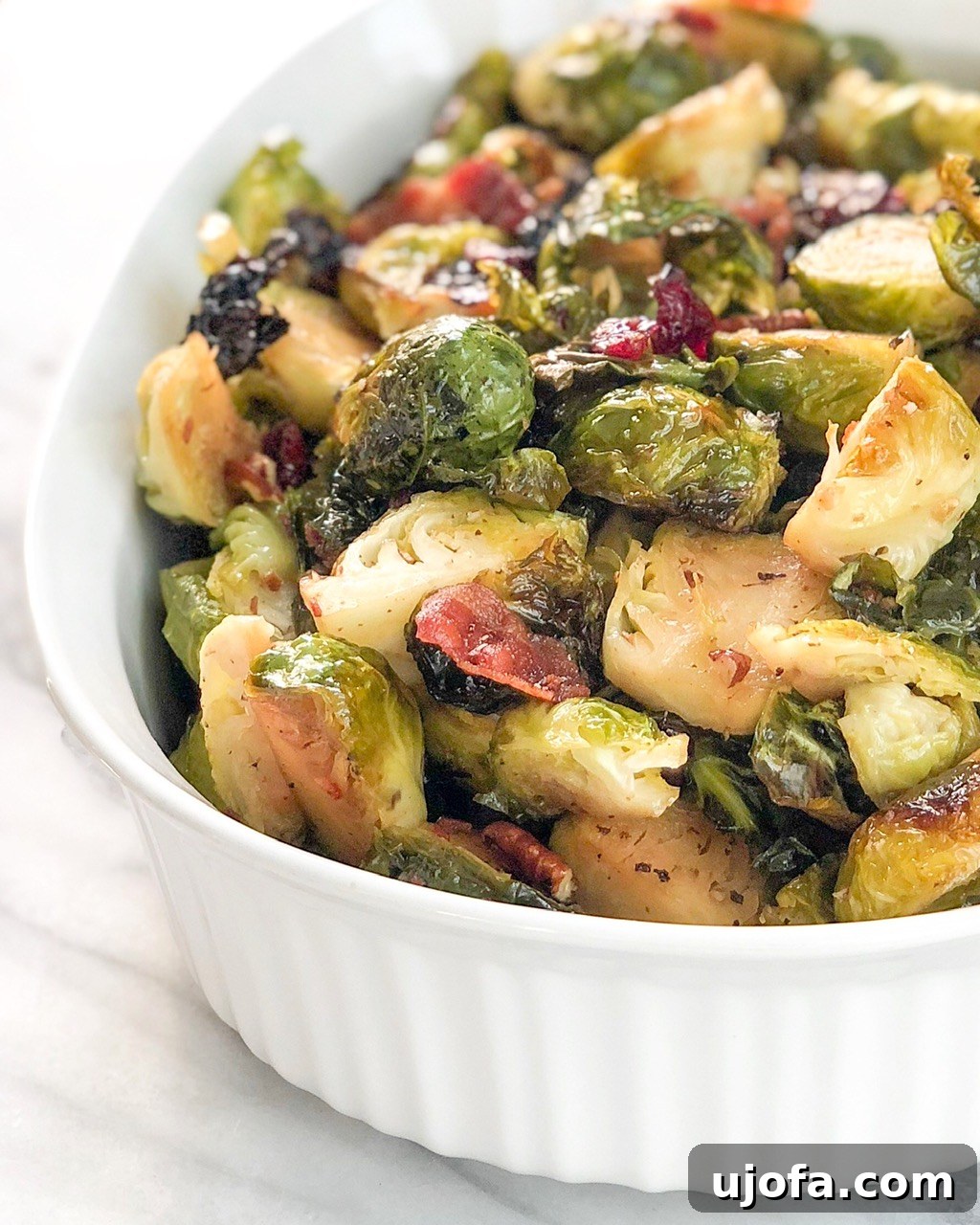 Muhteşem Paleo Şükran Günü Sofrası İçin Her Şey 12 A vibrant platter of roasted Brussels sprouts, generously coated with crispy bacon bits, tart cranberries, and crunchy pecans, glistening with a maple glaze.