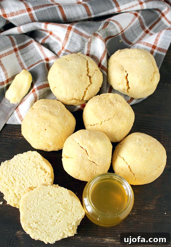 Muhteşem Paleo Şükran Günü Sofrası İçin Her Şey 4 Golden brown, flaky Paleo biscuits stacked on a rustic wooden board, some broken open to reveal their soft interior, hinting at a warm, comforting aroma.