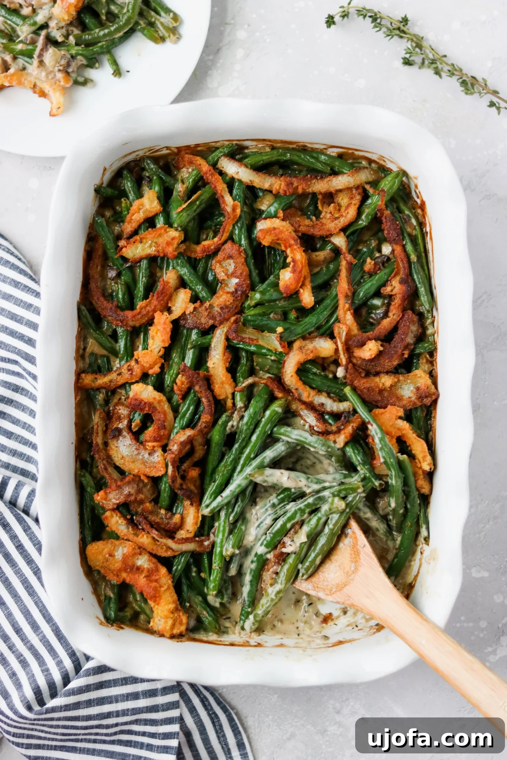 Muhteşem Paleo Şükran Günü Sofrası İçin Her Şey 5 A hearty, bubbly green bean casserole in a rustic baking dish, topped with crispy fried onions, ready to be served, showcasing its comforting appeal.