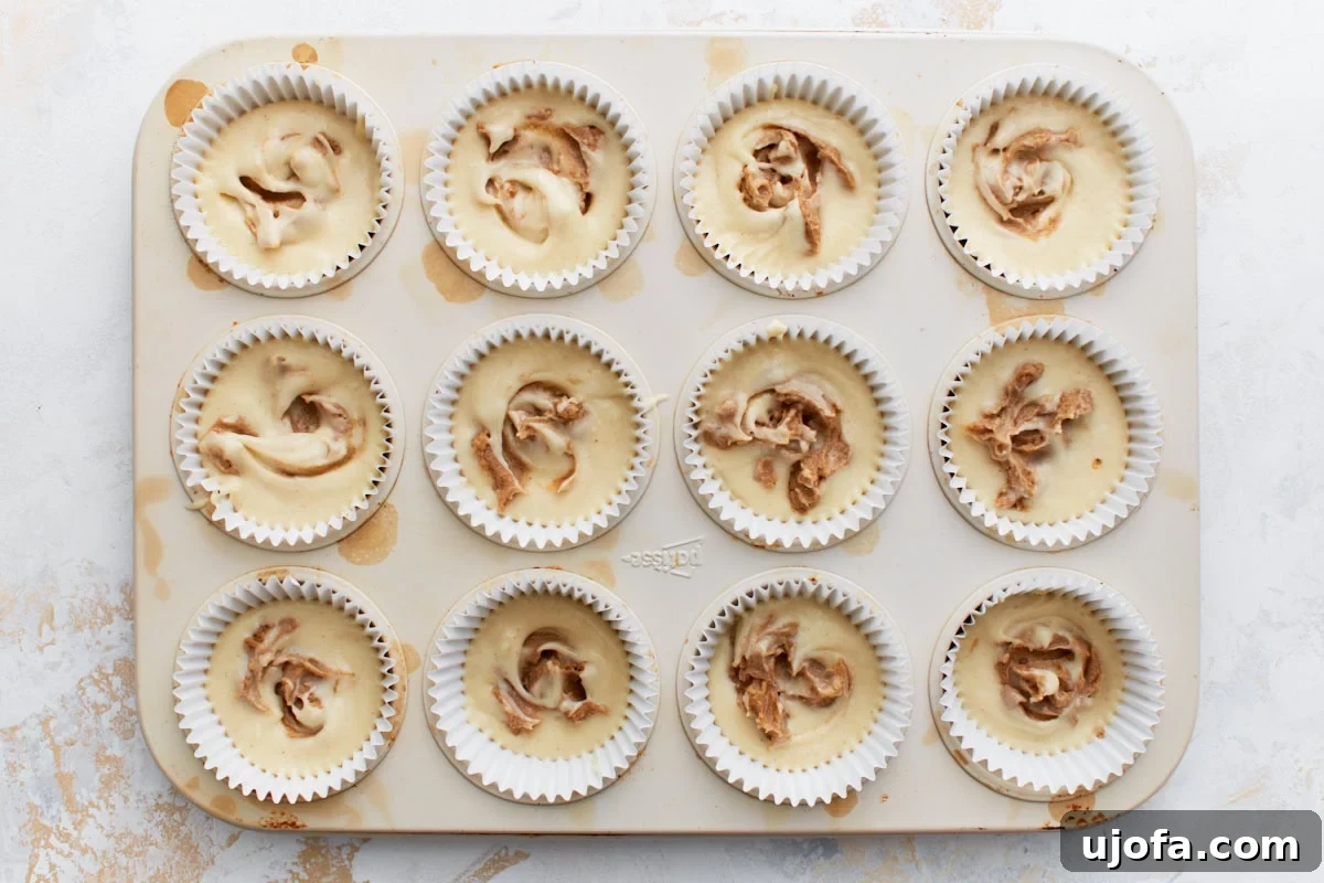 Gluten-Free Cinnamon Swirl Delights 10 Muffin tin showing batter with cinnamon topping swirled into each cup, creating a marbled effect.