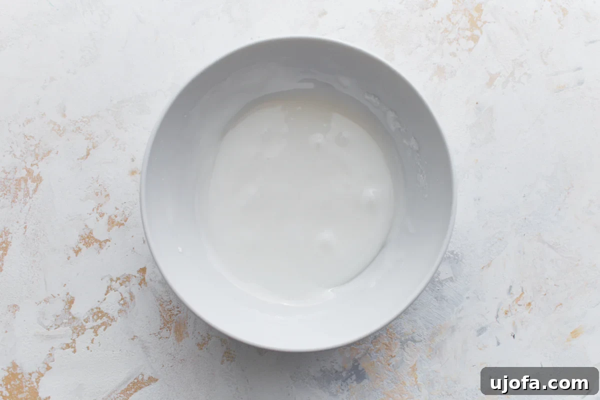 Gluten-Free Cinnamon Swirl Delights 12 White bowl containing smooth vanilla glaze, ready to be drizzled over the muffins.