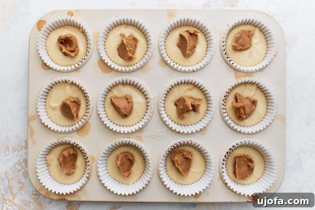 Gluten-Free Cinnamon Swirl Delights 9 Muffin tin with batter topped by spoonfuls of cinnamon sugar mixture, not yet swirled in.