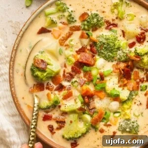 Loaded broccoli cheese & potato soup in a bowl with a spoon taking a bite out