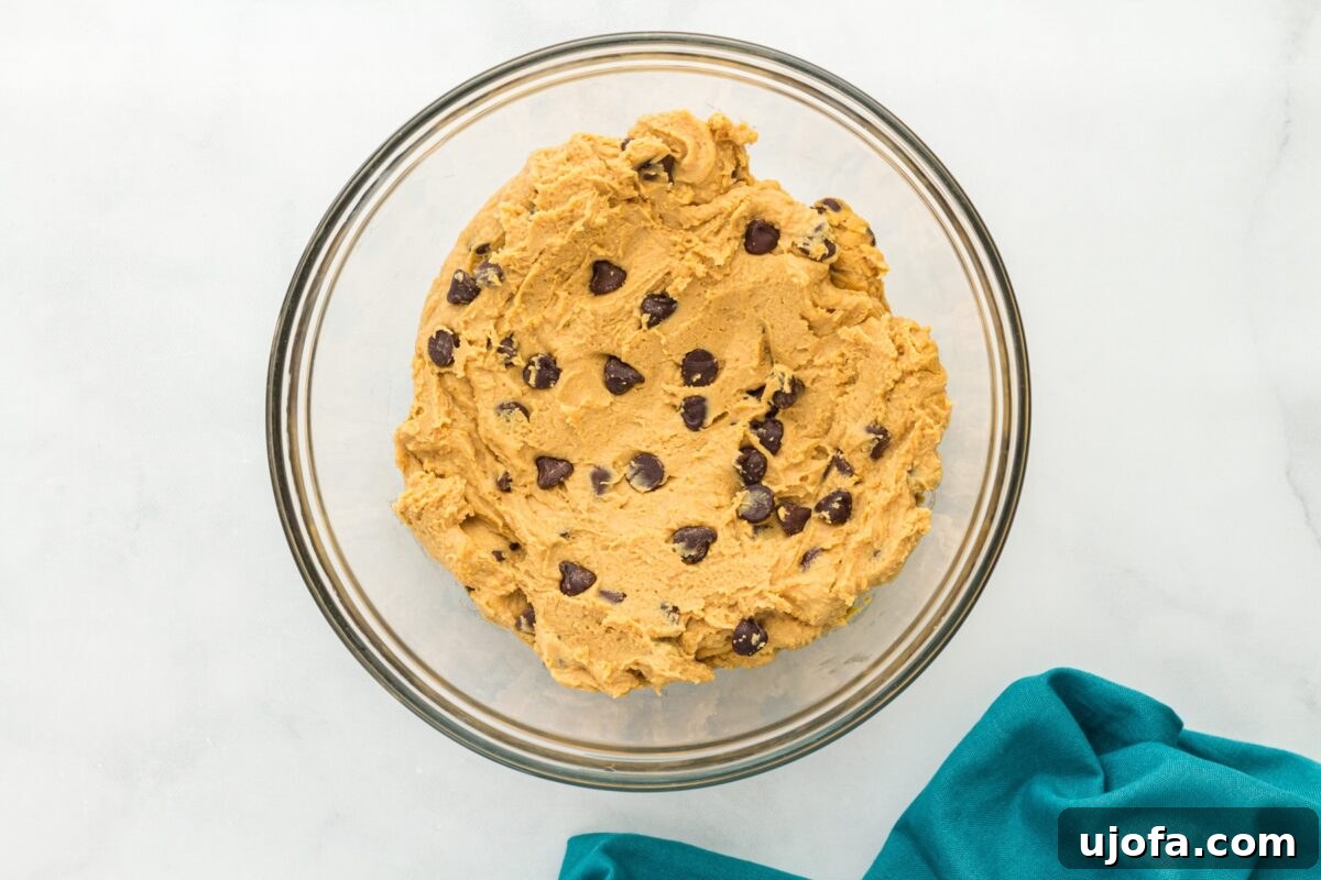 A glass bowl filled with chickpea-based edible cookie dough, mixed with chocolate chips.