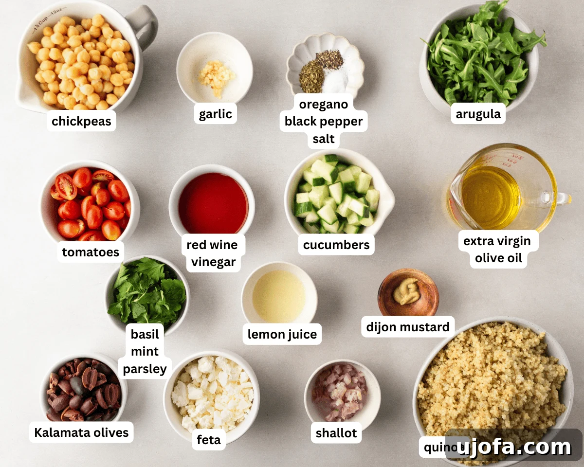 Greek quinoa salad ingredients laid out on a table: fresh vegetables, cooked quinoa, feta, olives, and dressing components.