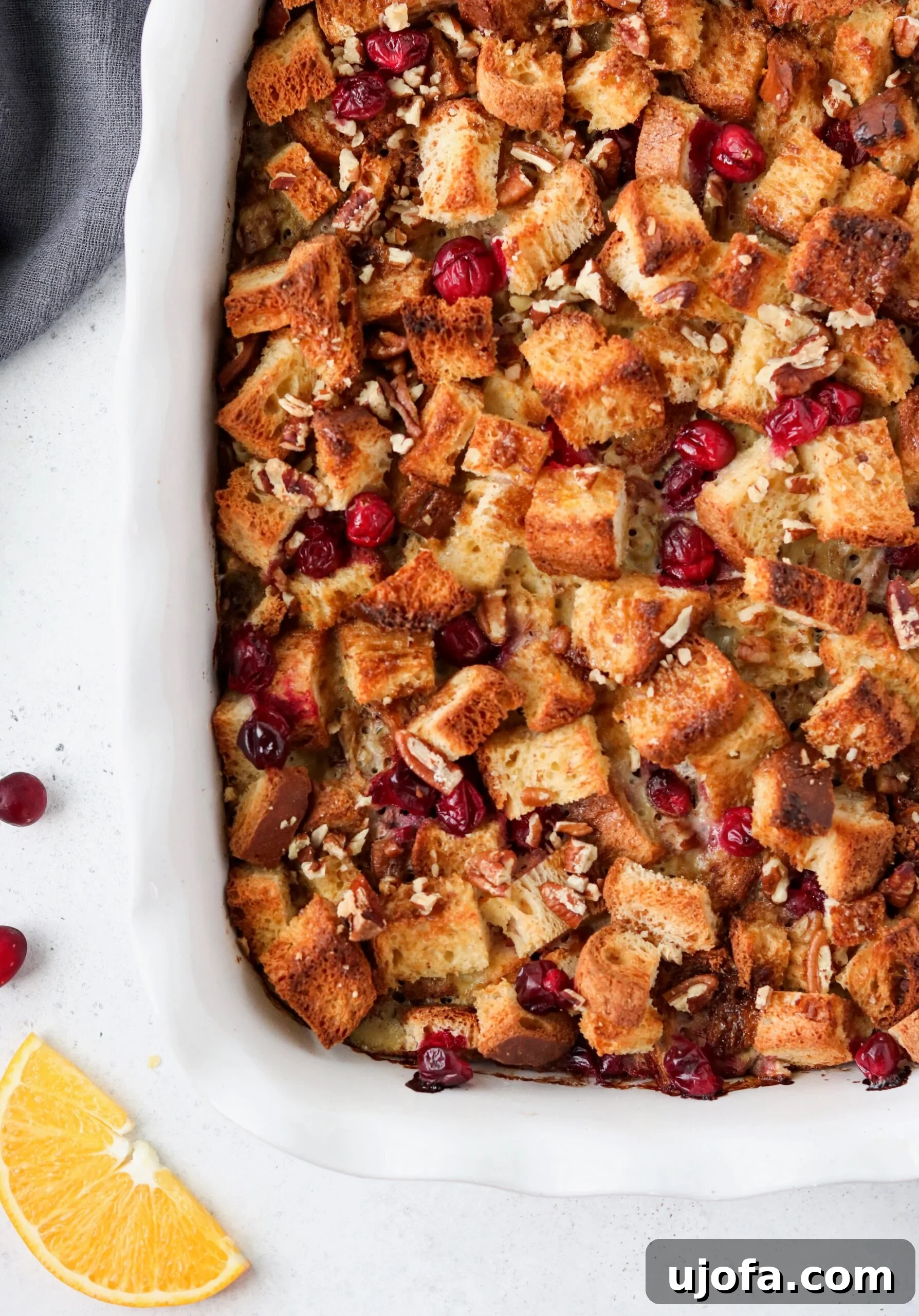Delicious Orange Cranberry Overnight French Toast Casserole ready to serve, showing a golden brown top with cranberries and orange zest.
