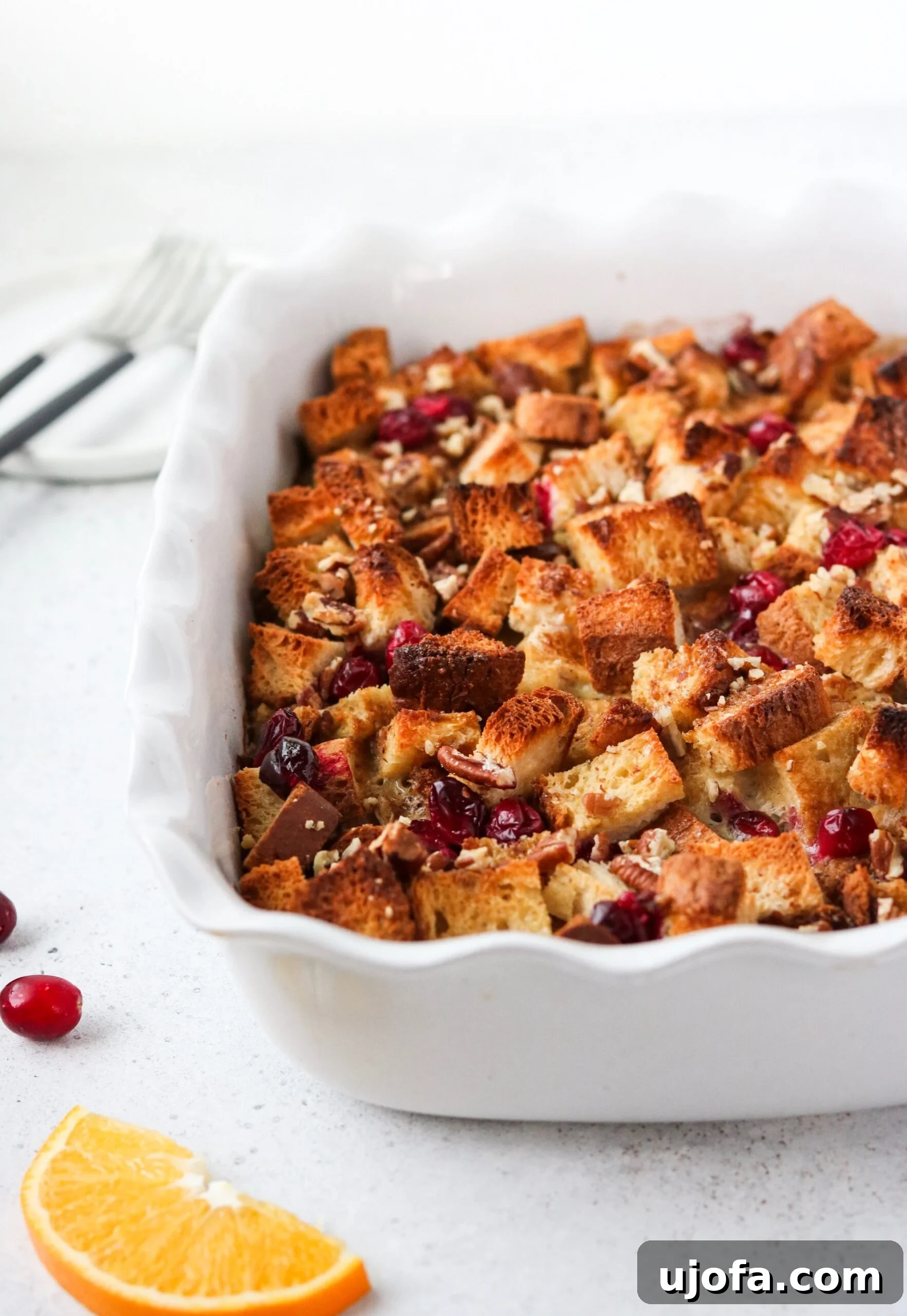 Overhead shot of Orange Cranberry Overnight French Toast Casserole, garnished with powdered sugar and fresh orange slices for presentation.