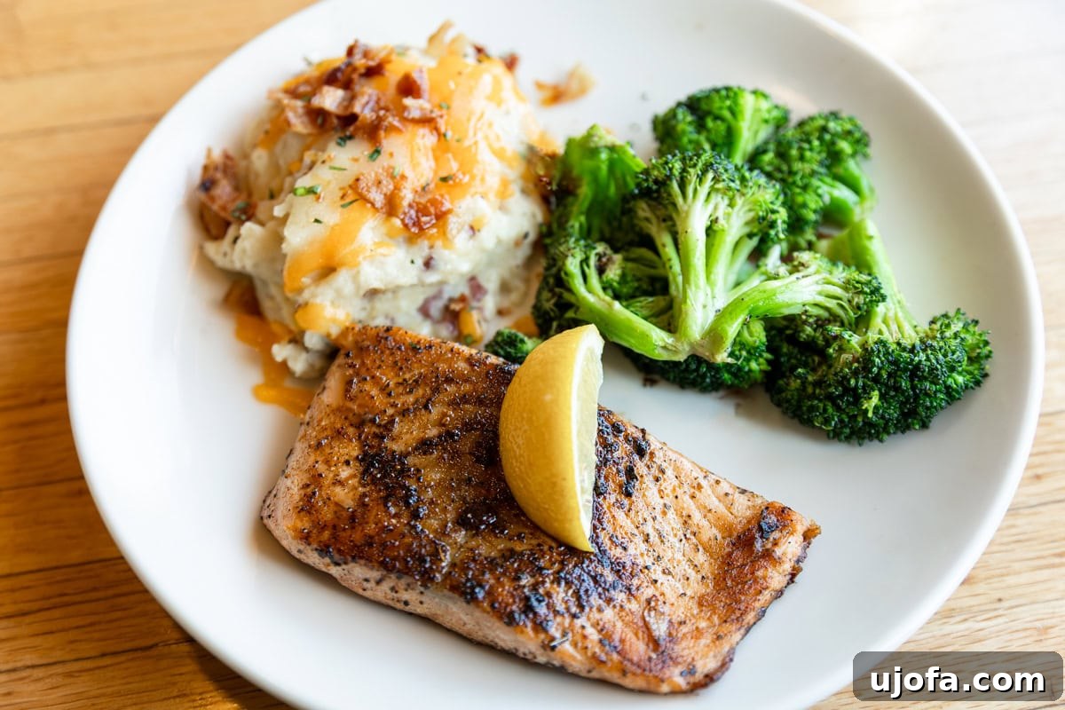 Applebees Gluten Free Dining 8 A perfectly seared Blackened Cajun Salmon fillet from Applebee's, garnished with fresh herbs and a lemon wedge, a delectable gluten-free seafood option.