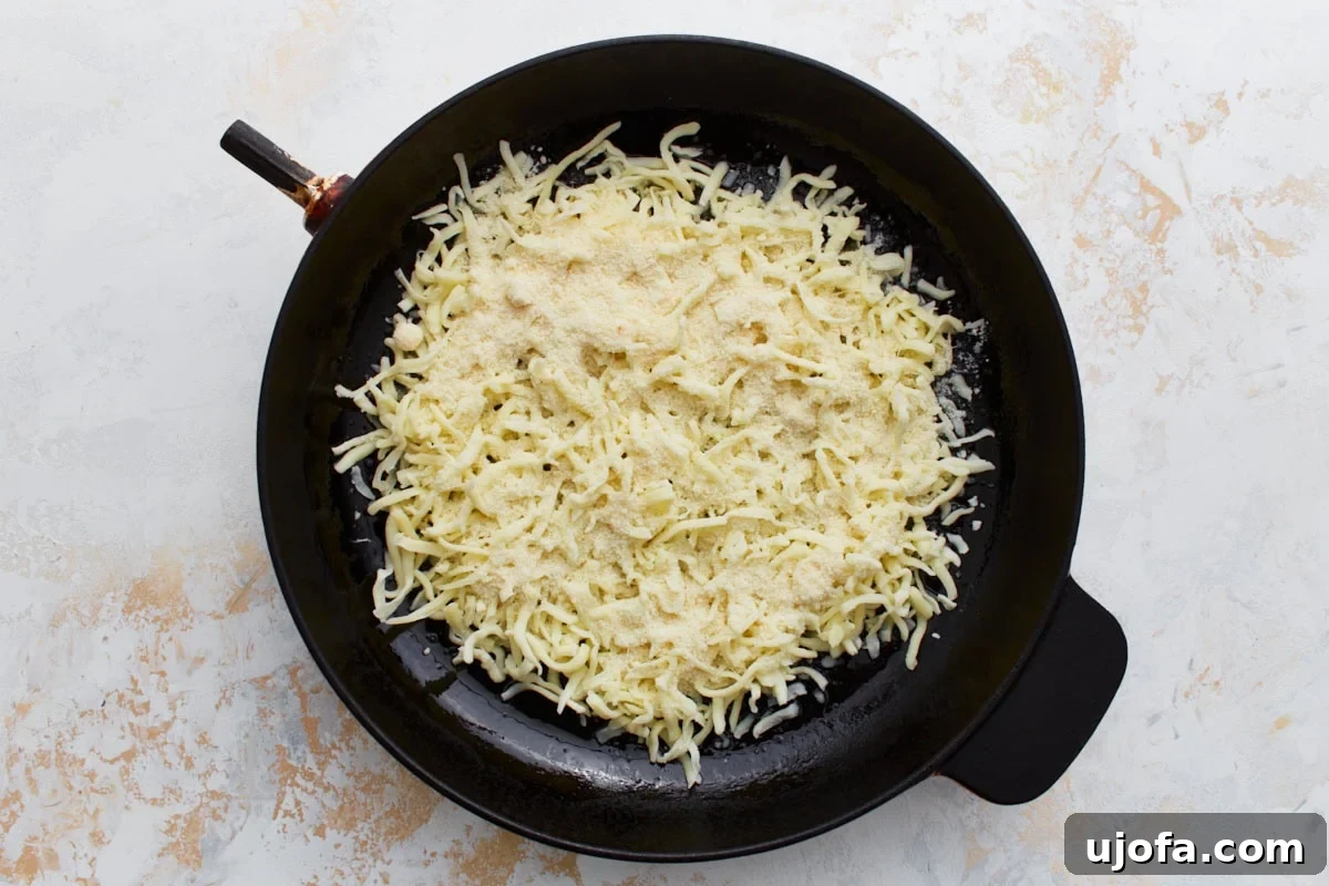 Pizza Bowl 5 Uncooked shredded mozzarella and grated Parmesan cheese spread evenly in a greased cast iron skillet, ready for seasoning and baking.