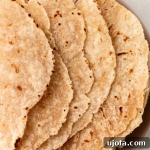 A stack of cooked cassava flour tortillas on a plate, showing lightly browned and slightly crisped edges.