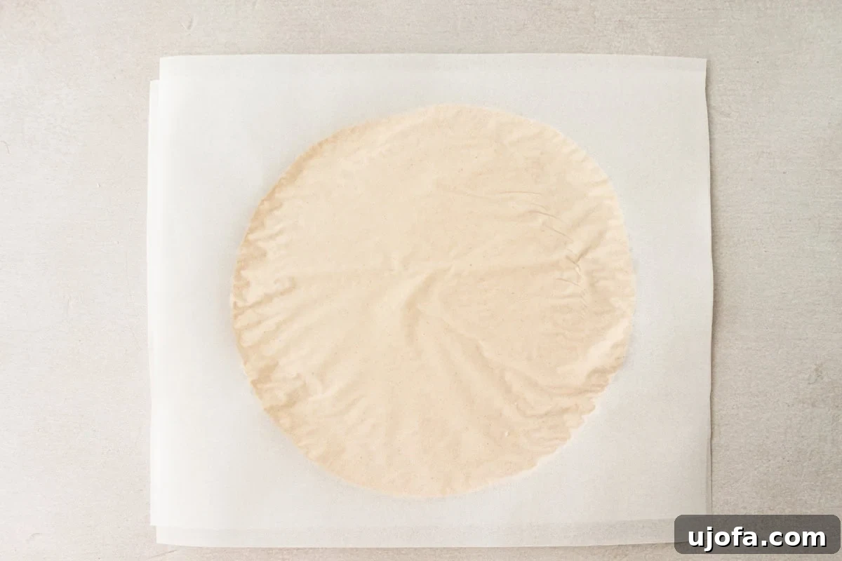 Grain-Free Cassava Wraps 8 A perfectly rolled-out cassava tortilla flattened between two pieces of parchment paper.