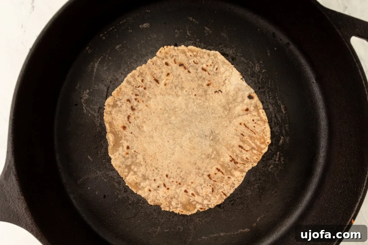 Grain-Free Cassava Wraps 9 A cassava tortilla cooking in a hot black cast-iron skillet, showing early signs of browning.
