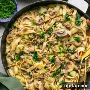 sausage and fennel pasta in a cast iron skillet with a green napkin next to it