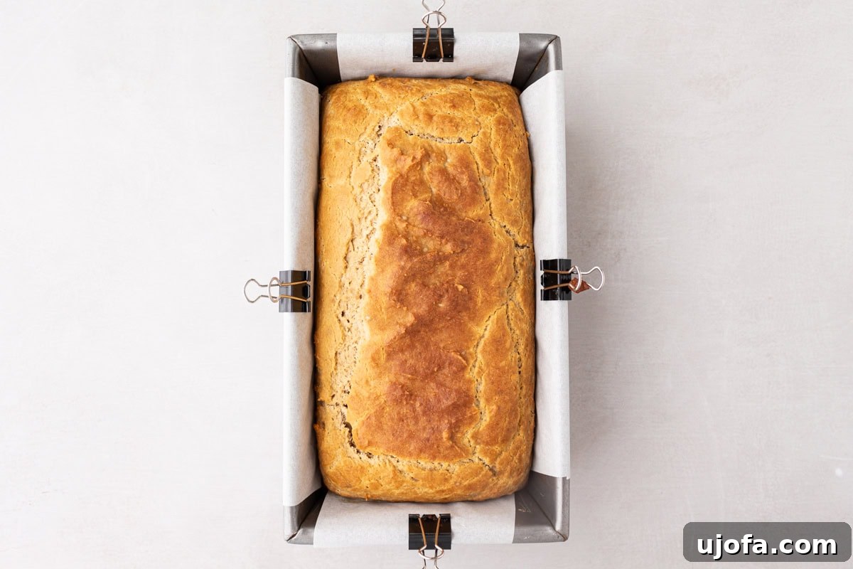 Tropical Root Bread 9 Freshly baked cassava bread in a loaf pan lined with parchment paper, showing a golden-brown top and firm edges.