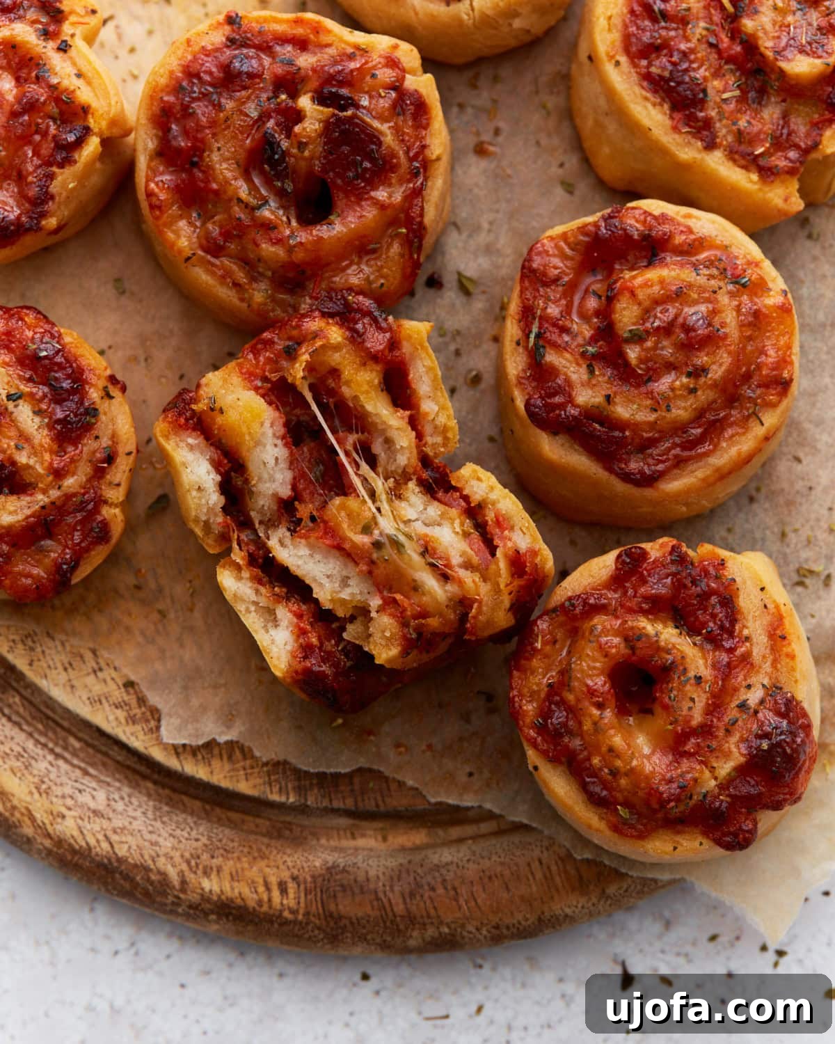 Close-up of golden-brown pizza rolls with melted cheese and tomato sauce, one roll torn open showing a gooey cheese pull. Perfect for a delicious gluten-free snack.