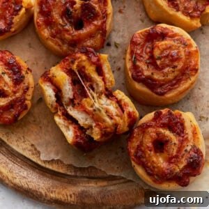 Close-up of golden-brown pizza rolls with melted cheese and tomato sauce, one roll torn open showing a gooey cheese pull.