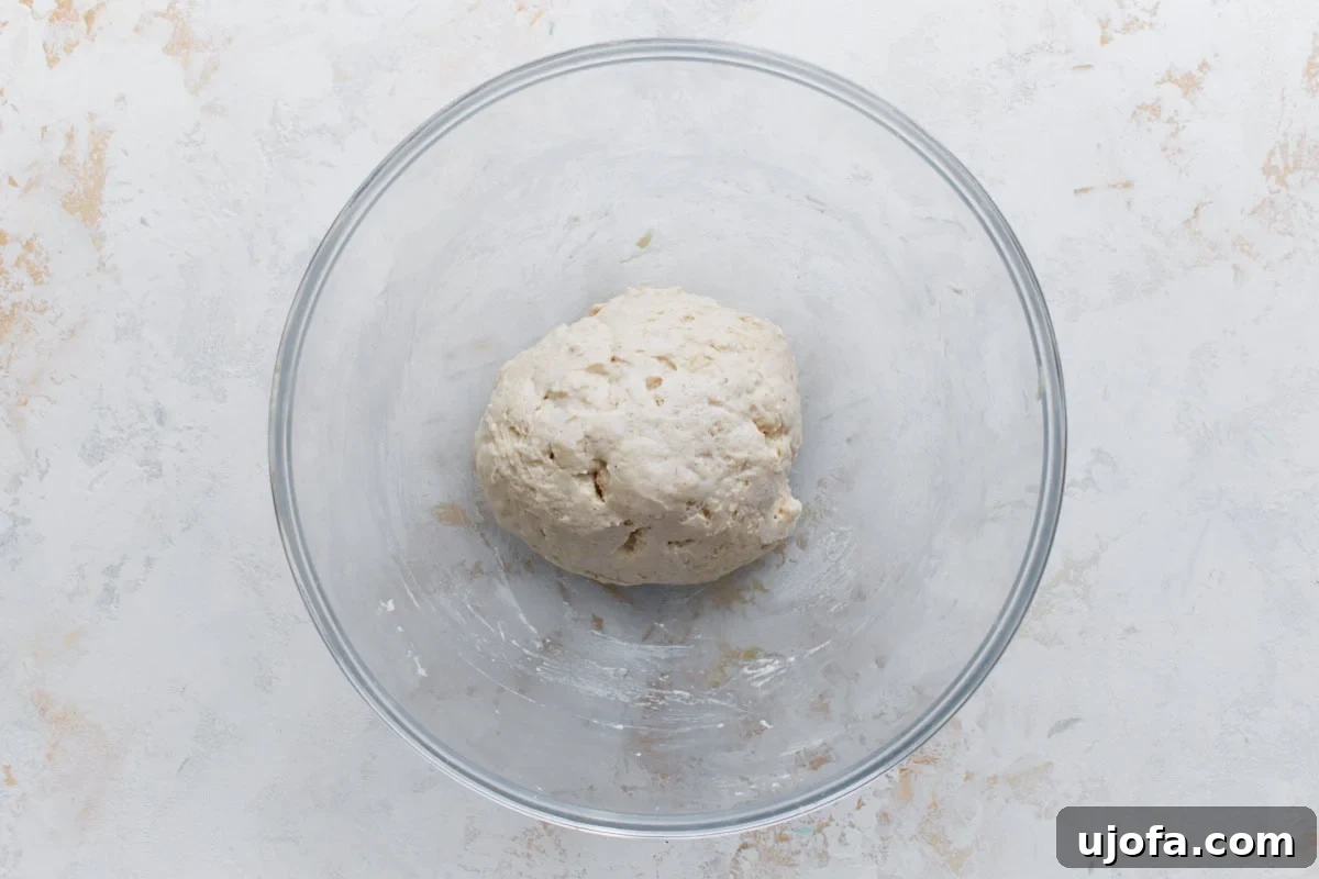 A smooth ball of gluten-free dough resting in a glass bowl, perfectly formed and ready to be rolled out for delicious pizza rolls.