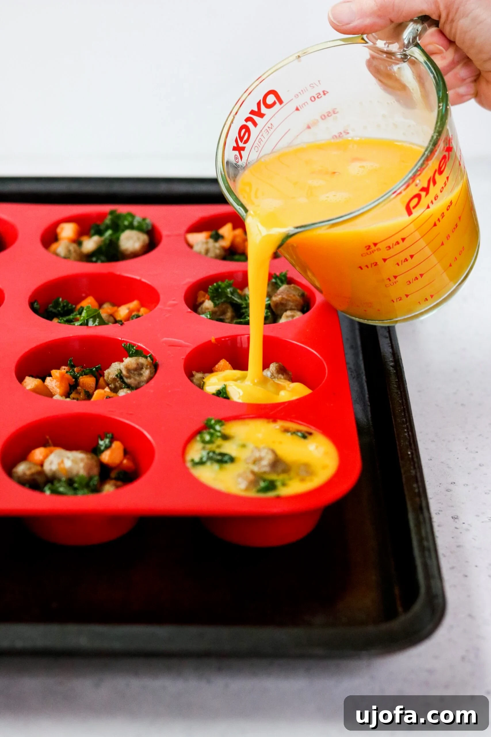 Savory Sausage, Sweet Potato, and Kale Egg Bites Whole30 Paleo 5 Assembled sausage, sweet potato, and kale egg cups in a silicone muffin pan, ready for baking.