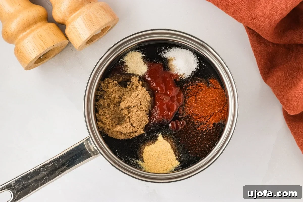Handcrafted Gluten-Free Barbecue Zest 5 A saucepan filled with BBQ sauce ingredients including brown sugar, ketchup, paprika, garlic powder, and other seasonings, before mixing. Wooden pepper mills and a rust-colored napkin are nearby.