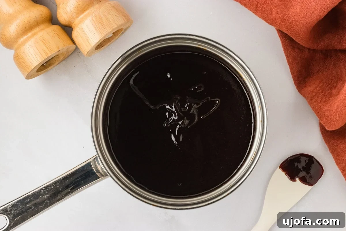 Handcrafted Gluten-Free Barbecue Zest 6 The BBQ sauce fully mixed and thickened in a saucepan, with a smooth, glossy finish. A white spatula with a bit of sauce sits on the counter beside it.