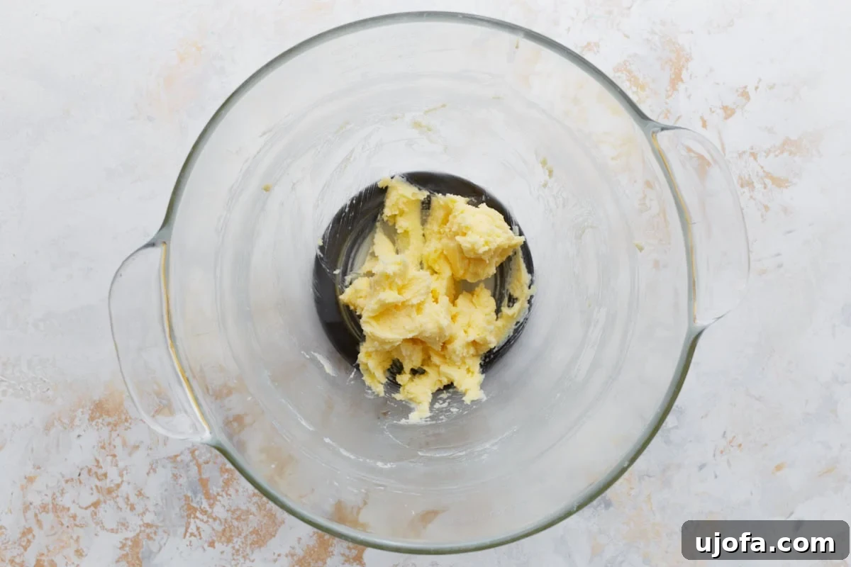 Pure Vanilla Gluten-Free Wafers 5 Softened butter creamed with sugar in a clear glass mixing bowl, forming a pale yellow mixture.
