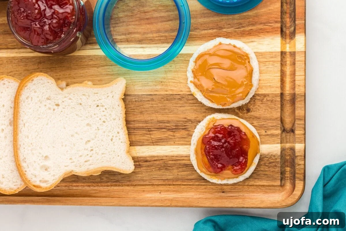 GF Lunchbox Wonders 7 One bread circle spread with peanut butter and another with peanut butter and strawberry jam, ready to be assembled into a sandwich.
