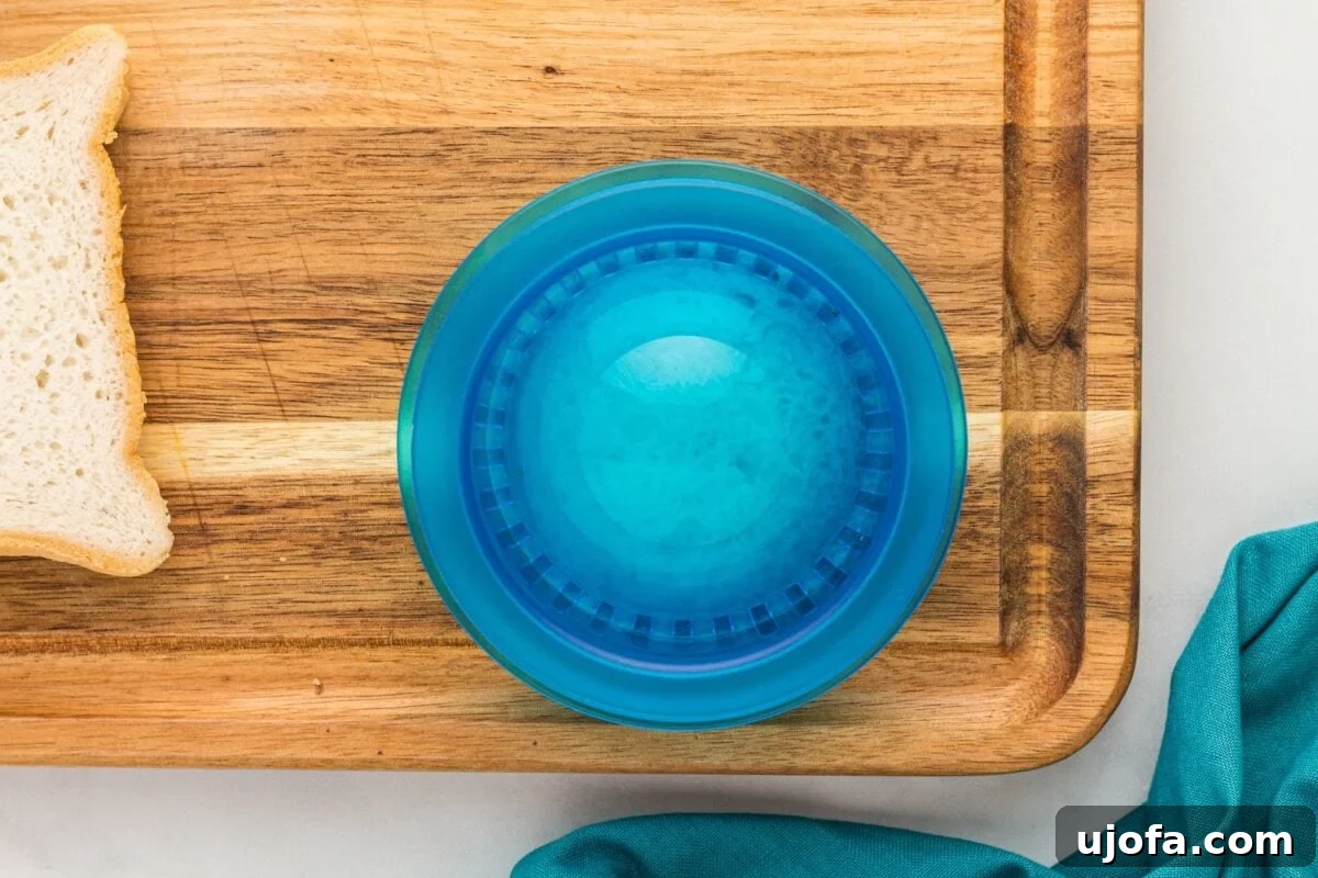GF Lunchbox Wonders 8 A blue sandwich press placed over a filled sandwich on a wooden cutting board, sealing the uncrustable.