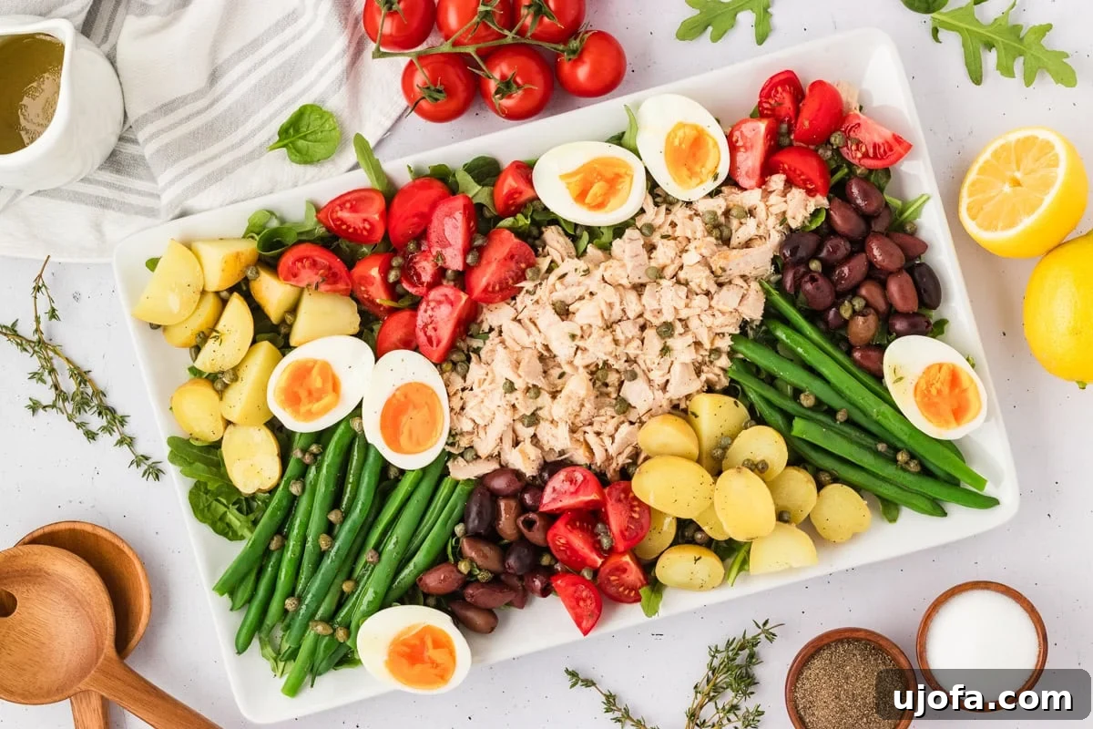 French Riviera Tuna Salad 12 Overhead view of the completed Tuna Nicoise Salad, styled with fresh thyme, lemons, tomatoes, and dressing on the side.