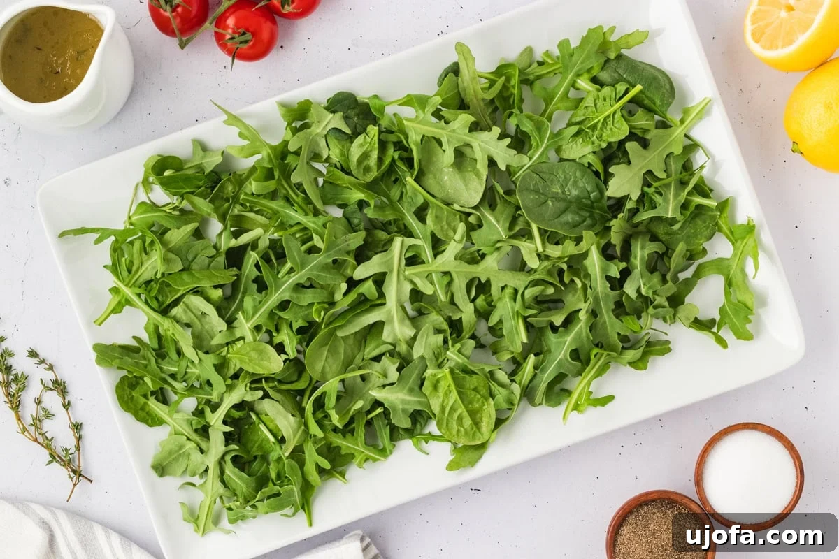 French Riviera Tuna Salad 9 Fresh arugula and spinach mix laid out on a white rectangular platter, ready to be topped for Tuna Nicoise Salad.