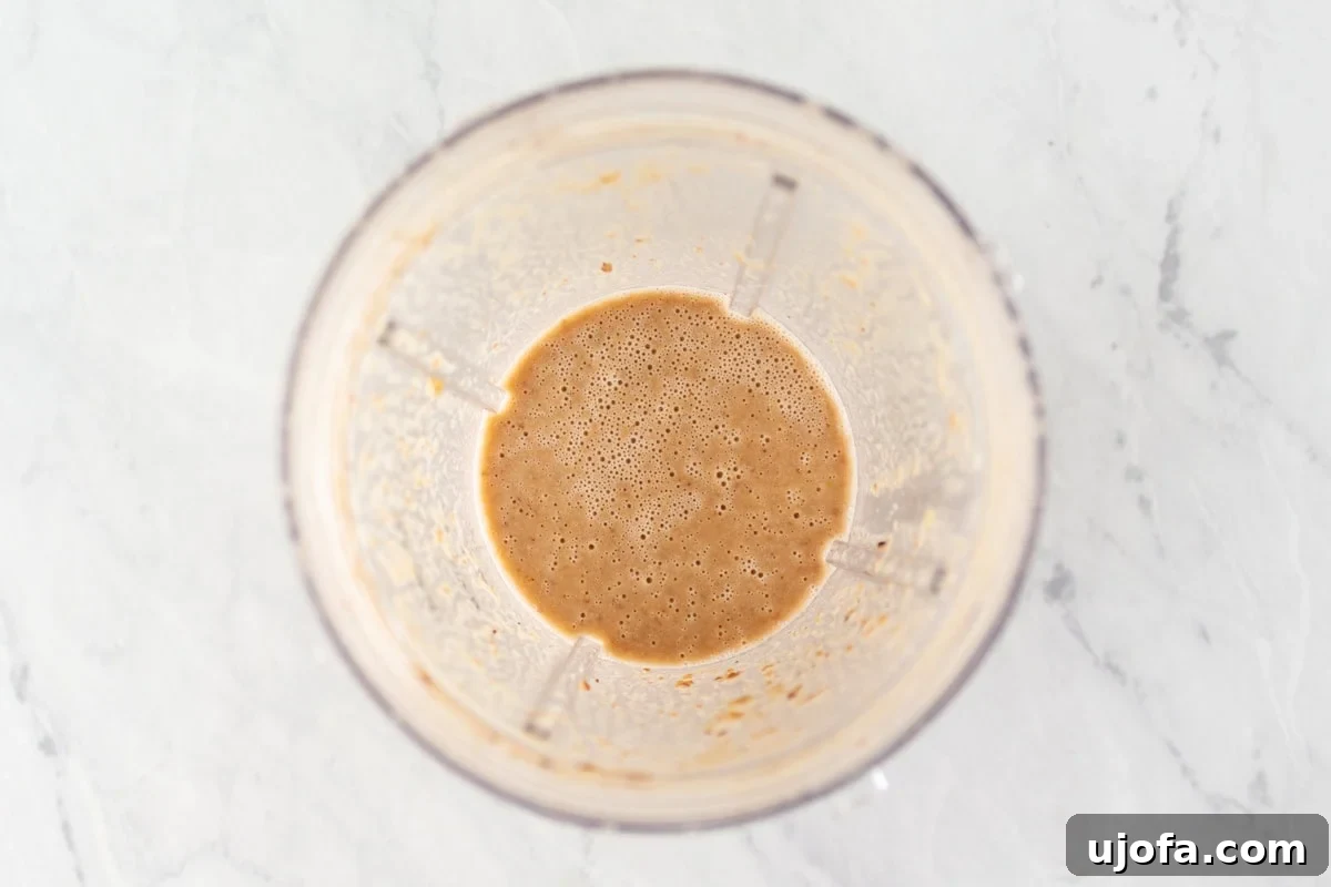 Gluten-Free Worcestershire from Scratch 7 A blender cup filled with a light brown, frothy mixture after blending the sautéed ingredients, raisins, and vinegar.