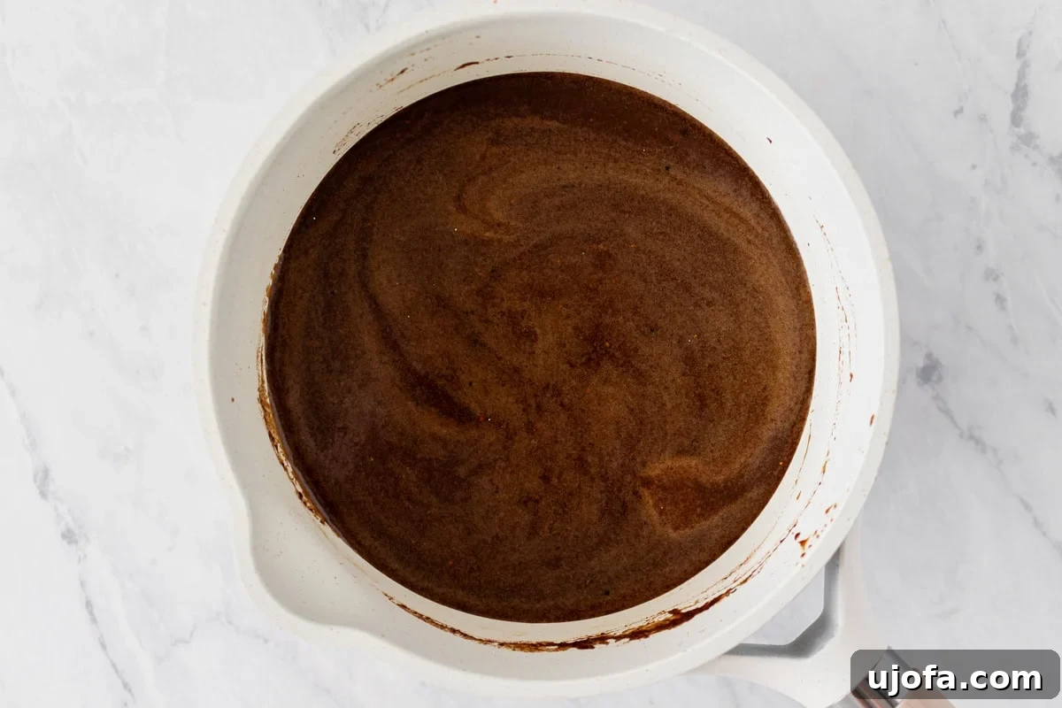 Gluten-Free Worcestershire from Scratch 9 A saucepan with the Worcestershire sauce simmering and darkening as it thickens on the stove.