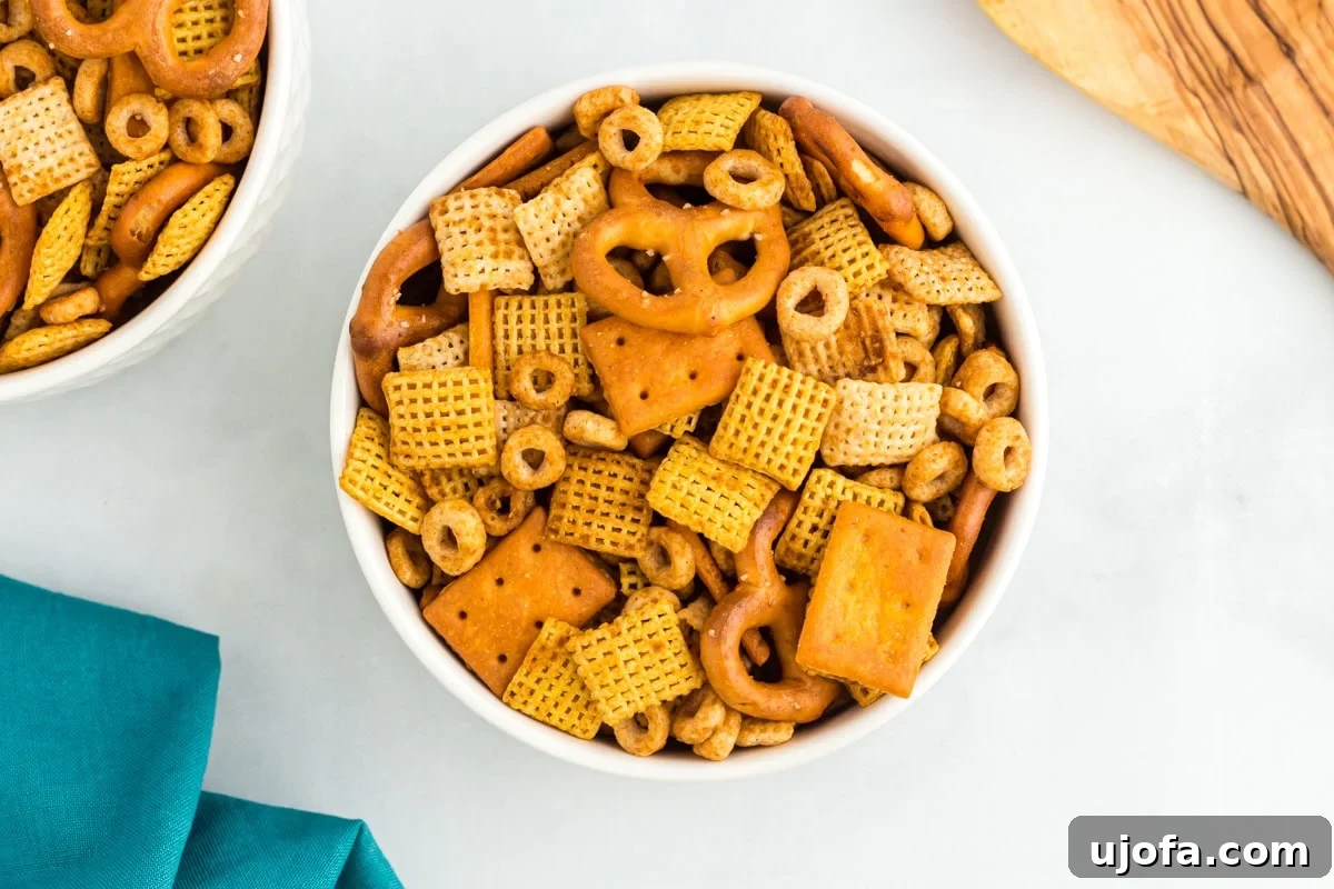 Savory Gluten-Free Party Mix 9 White bowl filled with gluten-free Chex Mix, highlighting the crunchy texture of cereal squares, mini pretzels, and crackers.