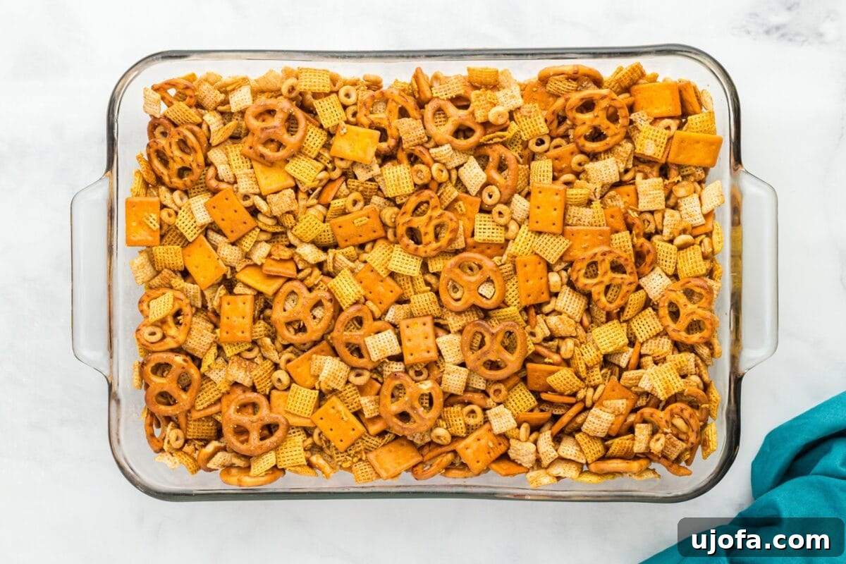 Savory Gluten-Free Party Mix 6 Top-down view of Chex Mix in a glass dish after baking, golden and evenly coated with seasoning.