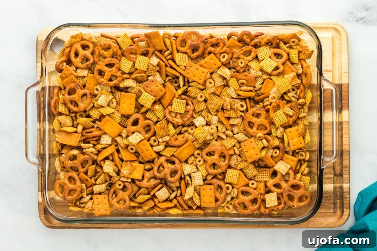 Savory Gluten-Free Party Mix 7 Baked gluten-free Chex Mix spread out in a glass dish resting on a wooden cutting board.