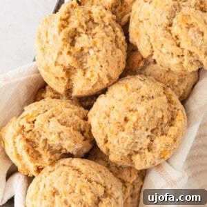 A basket filled with freshly baked gluten-free drop biscuits, nestled in a light kitchen towel.