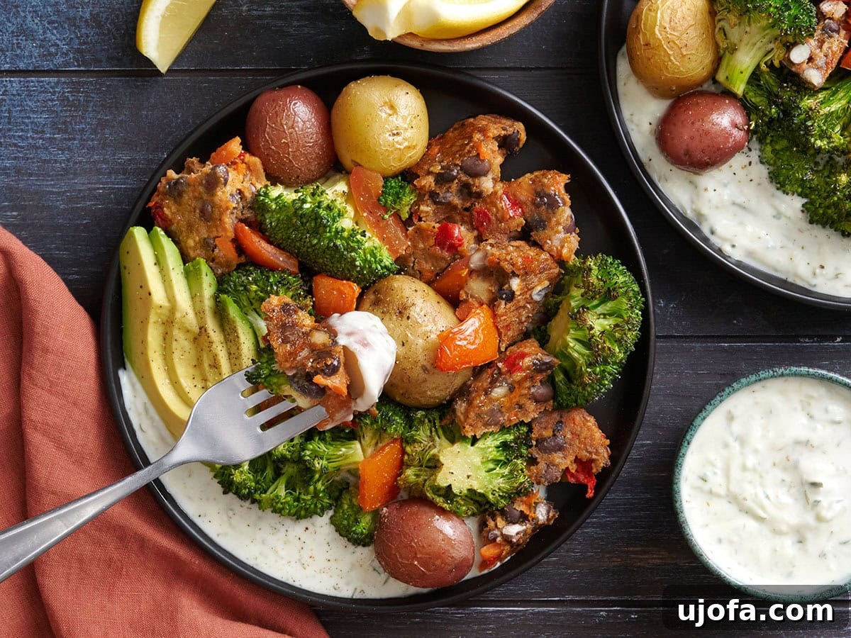 Tangy Tzatziki Black Bean Power Bowl 10 Overhead view of a homemade Tzatziki Black Bean Burger Bowl with a fork taking some, showcasing the layers of roasted vegetables, black bean burger, and creamy tzatziki.