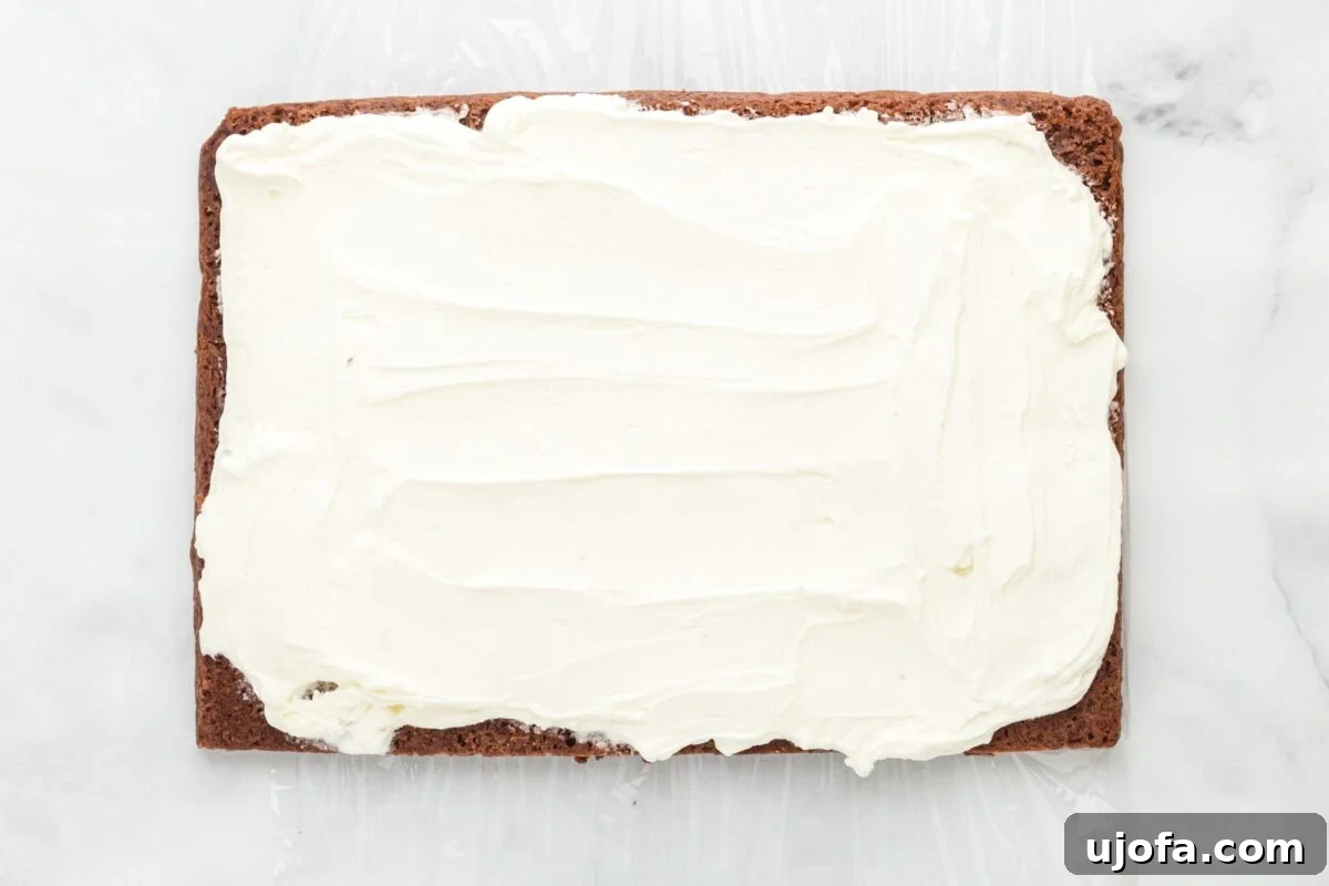 One half of the rich chocolate cookie base, perfectly chilled, is generously topped with a thick, smooth layer of softened vanilla ice cream, spread evenly to the edges.