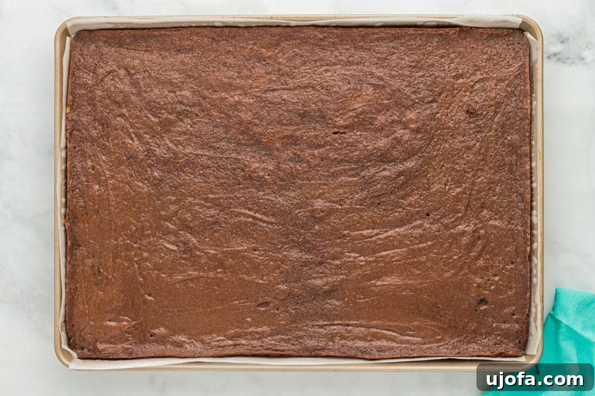 The fully baked chocolate cookie base, cooled and set, resting on the parchment paper within its baking sheet, ready for the next crucial step of chilling.