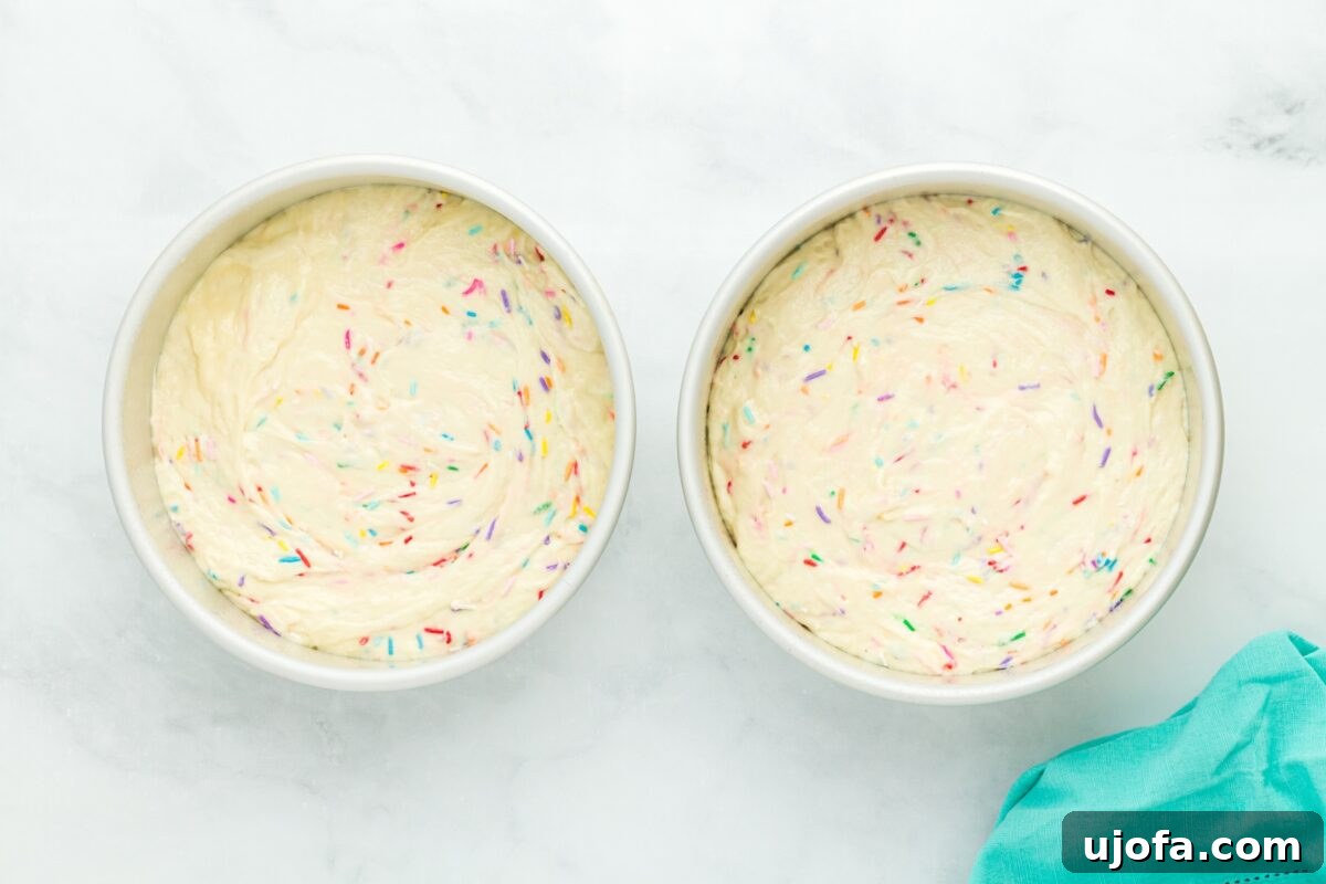 Two 8-inch round cake pans filled with funfetti batter, ready for the oven.
