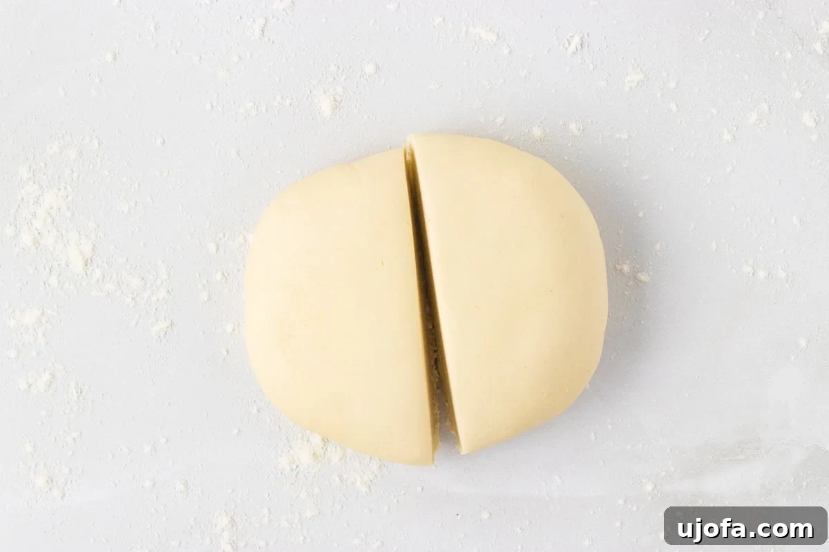 Rested dough ball cut in half on a lightly floured surface
