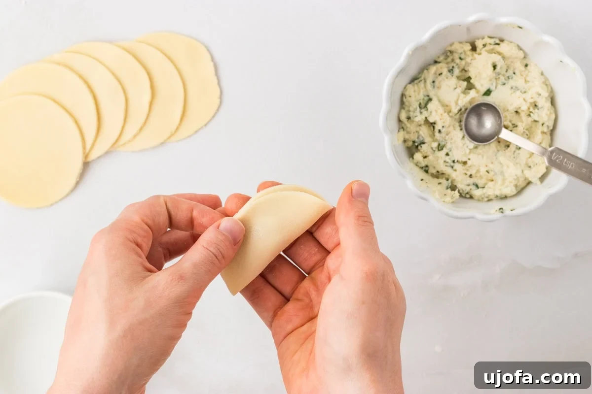Folding a pasta round in half to seal the ricotta filling inside for gluten-free tortellini
