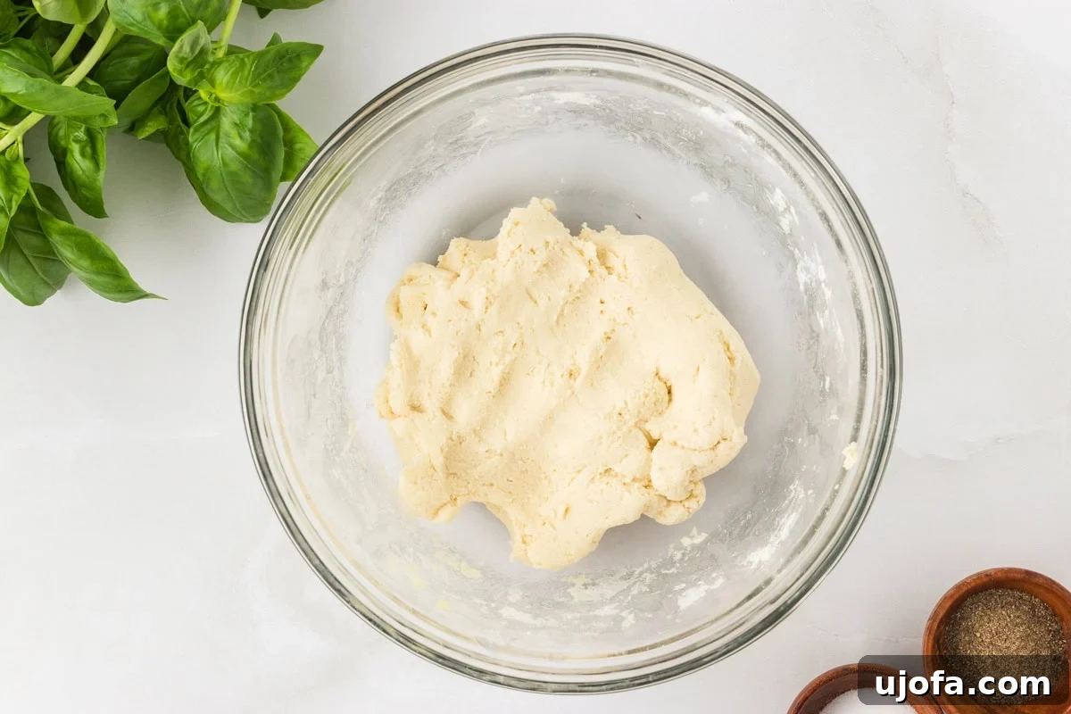 Ball of gluten-free pasta dough mixed and resting in a glass bowl