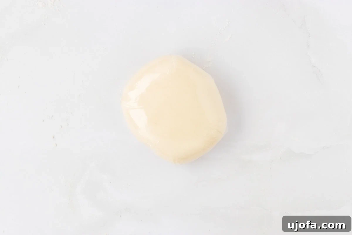 Gluten-free pasta dough wrapped tightly in plastic wrap on a white surface