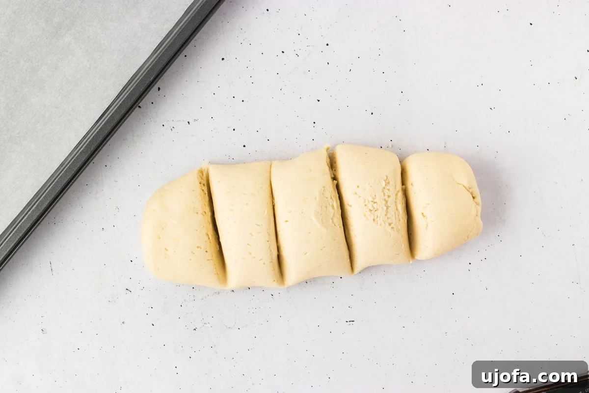 Gluten-free breadstick dough meticulously divided into ten equal pieces on a white counter, prepared for individual shaping.