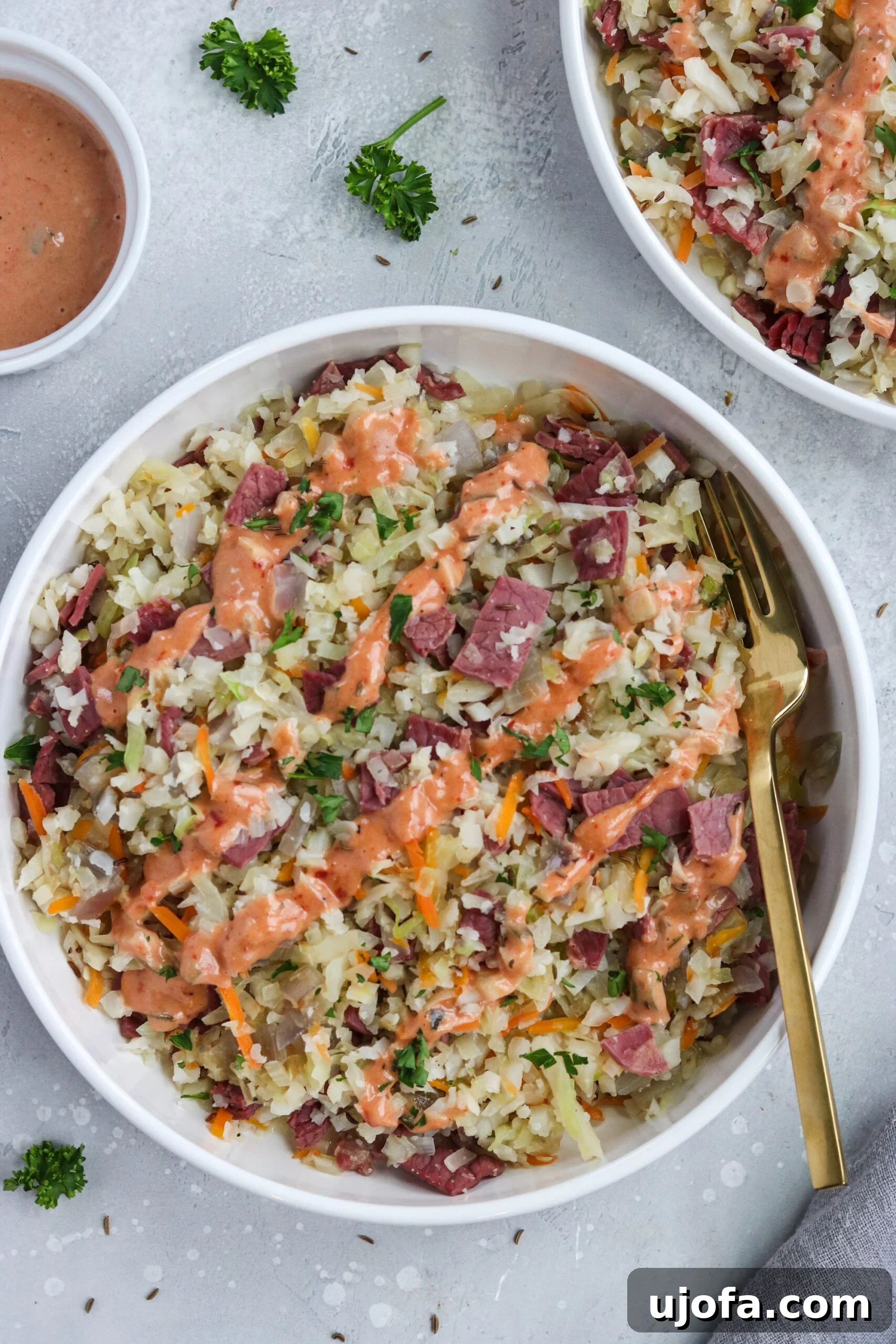 A vibrant and healthy Reuben in a Bowl with corned beef, cabbage, cauliflower rice, and a drizzle of Thousand Island dressing