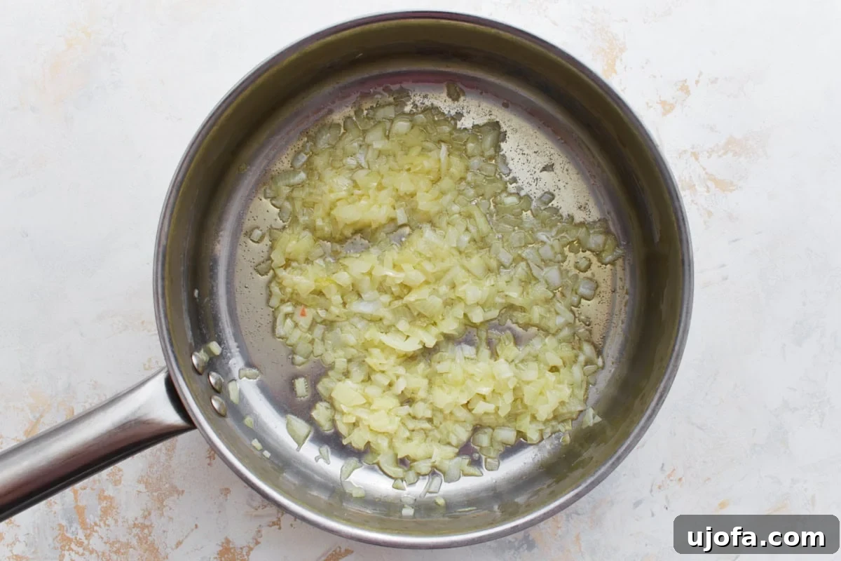Gluten-Free Risotto Bliss 5 Finely chopped onions sautéing in olive oil and butter in a stainless steel pan, becoming soft and translucent.