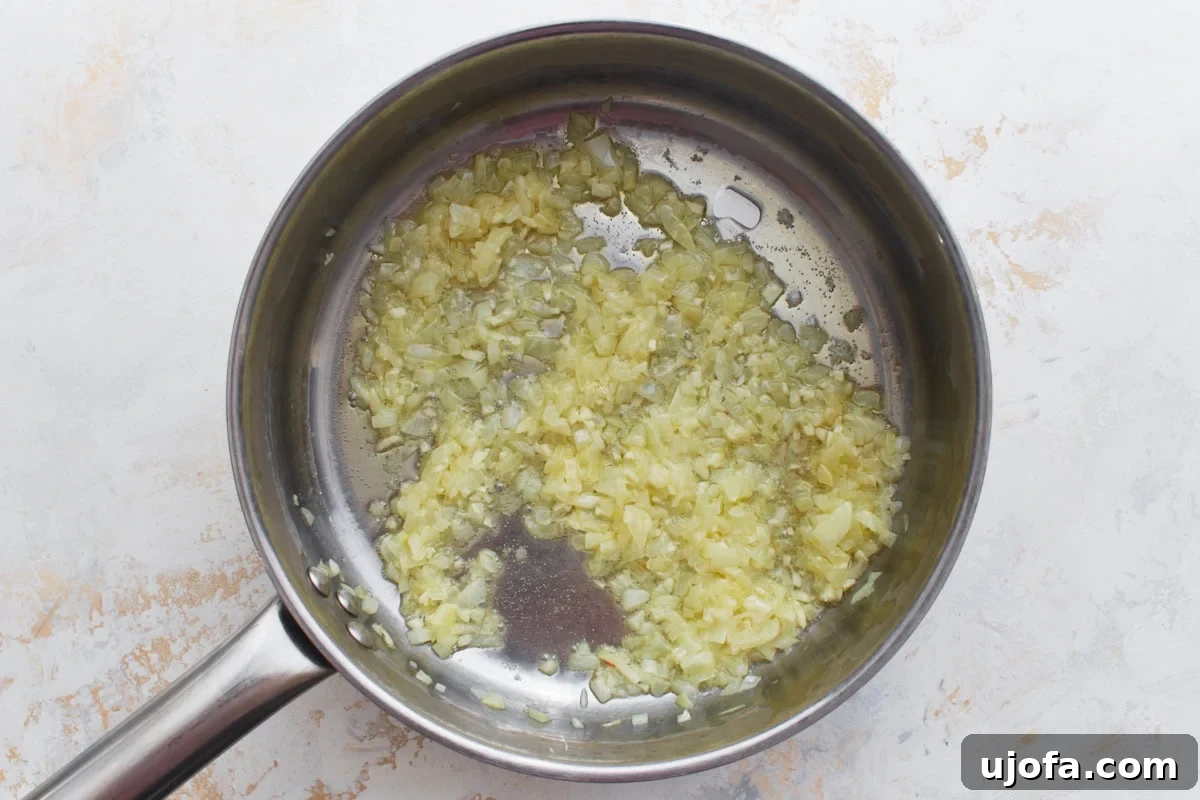 Gluten-Free Risotto Bliss 6 Sautéed onion and garlic mixture releasing a fragrant aroma in a pan, preparing for the rice addition.