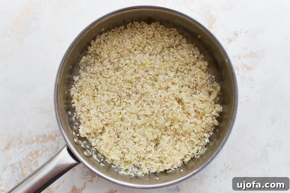 Gluten-Free Risotto Bliss 7 Arborio rice freshly added to the pan with sautéed onions and garlic, ready to be toasted and absorb flavors.