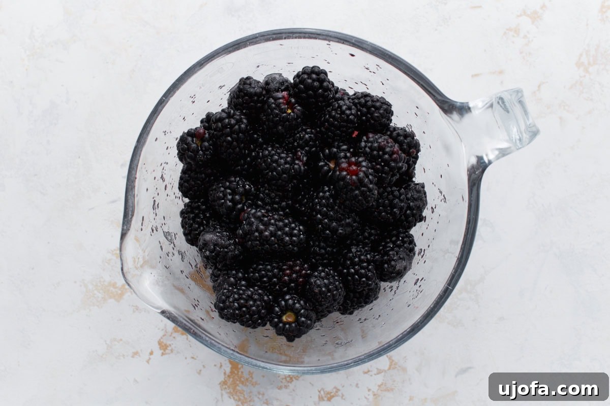A glass measuring cup filled with plump, fresh blackberries, ready for the cobbler filling.