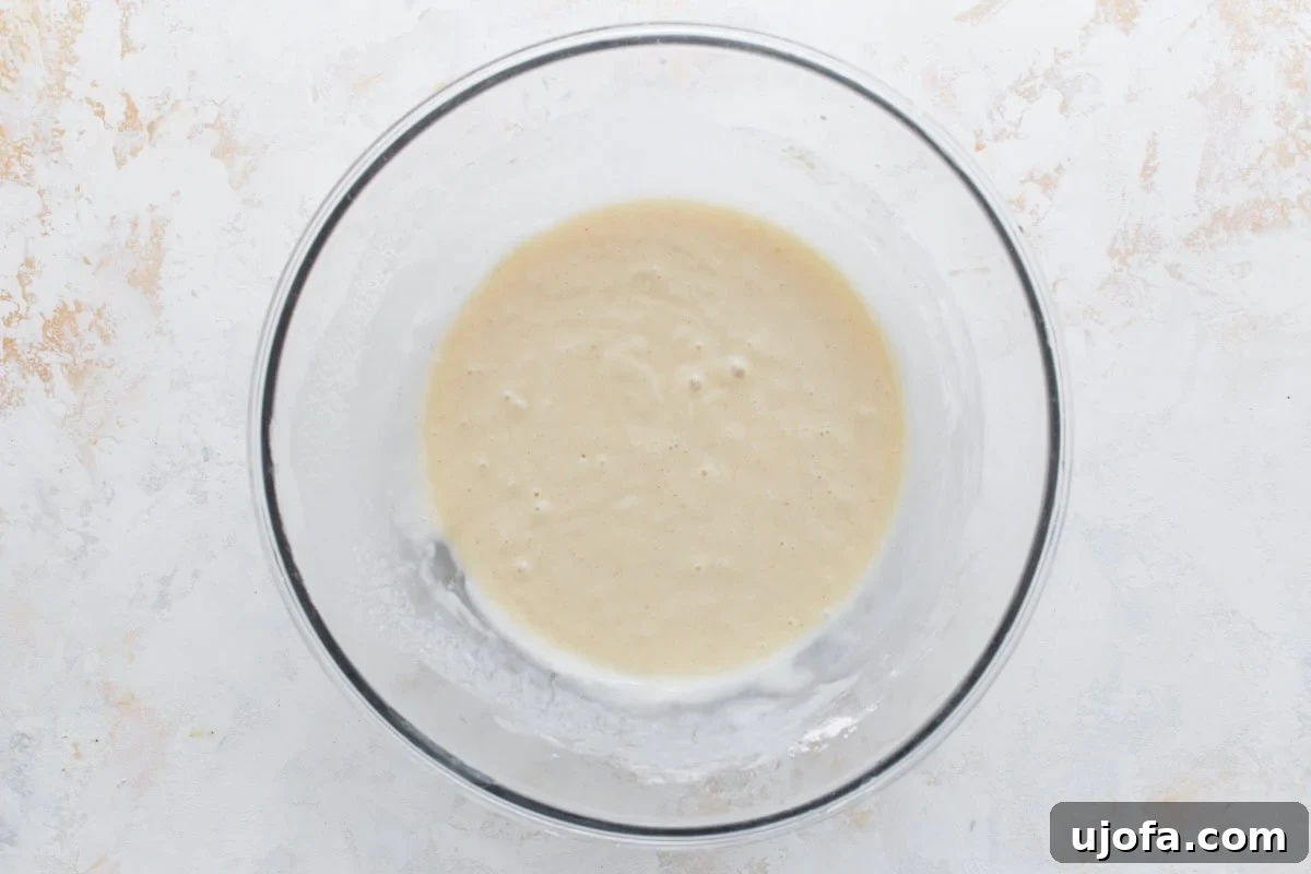A bowl of smooth, pale yellow cobbler batter, whisked to perfection and ready to be poured.